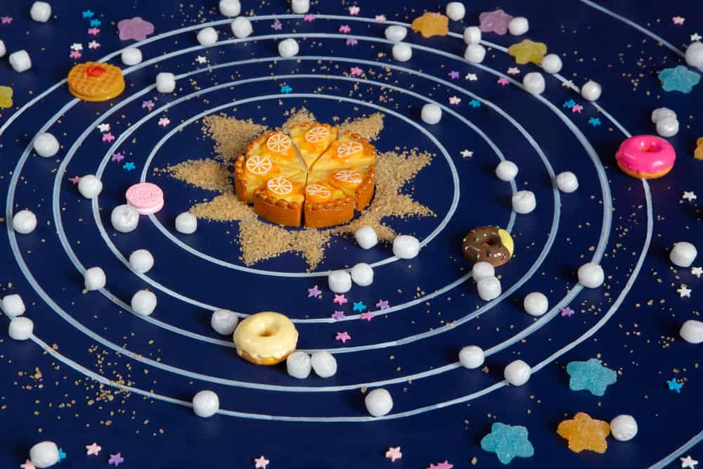 50 Best Space Activities for Kids 3 Solar system layout using cupcakes, donuts, marmalade, marshmallows, and cane sugar.
