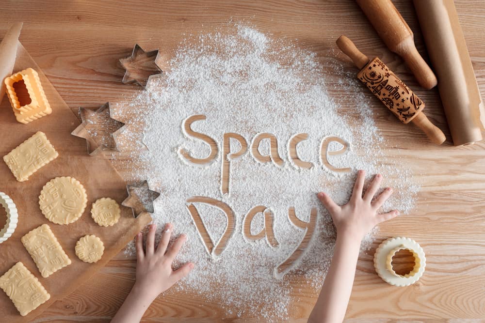 Space Day concept using homemade cookies and flour set on a wooden table.