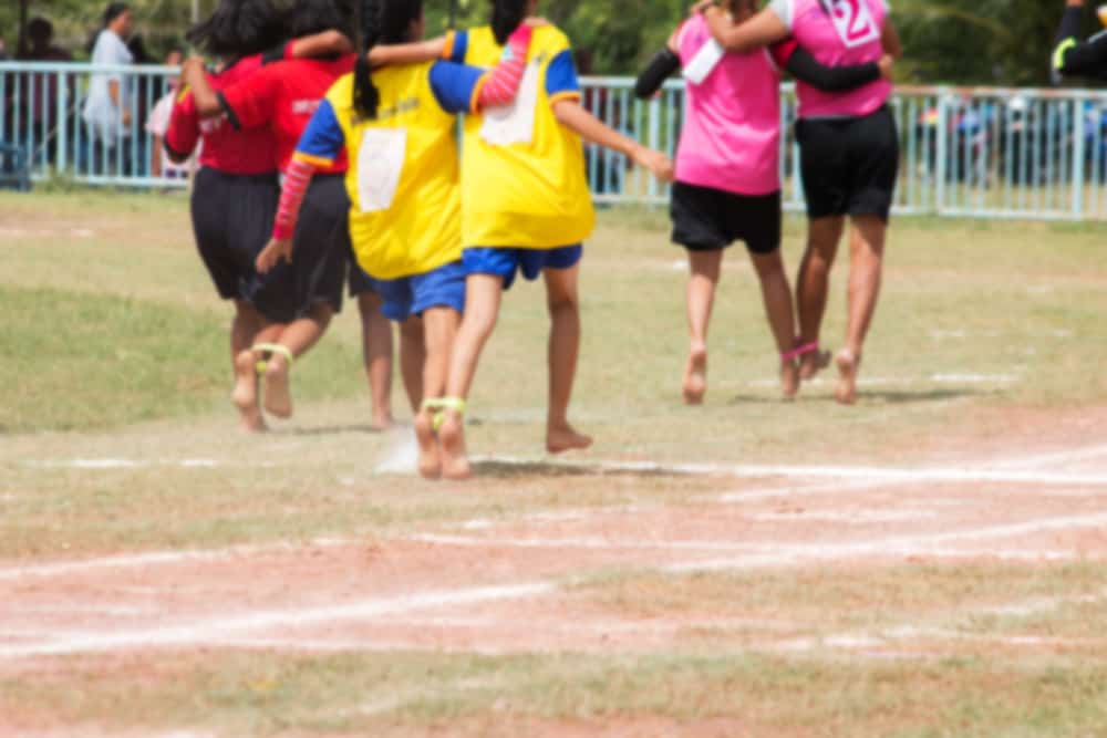 50 Best Group Activities For Kids 4 Three pairs of children compete in a three-legged race.