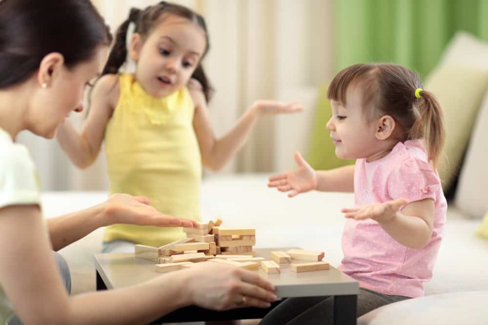 50 Best Group Activities For Kids 5 A mother and her daughters are playing Action Jenga.