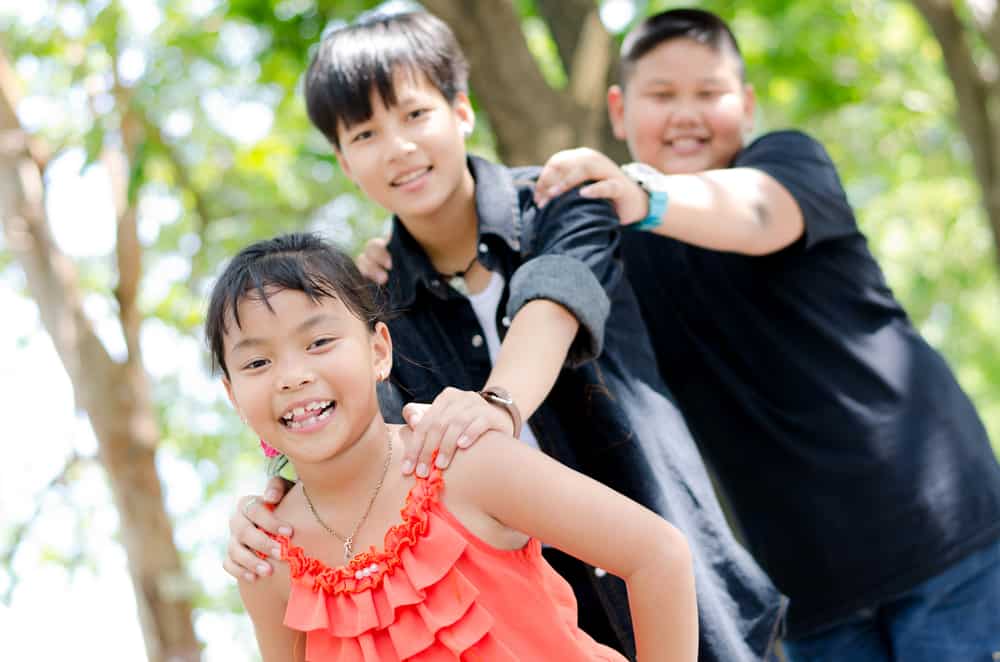 50 Best Group Activities For Kids 6 Three children playing in a wooded area as a train.