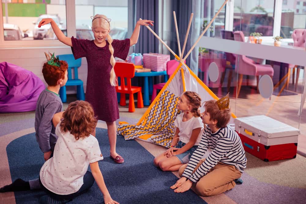 50 Best Group Activities For Kids 9 The children in the playroom are playing charades.