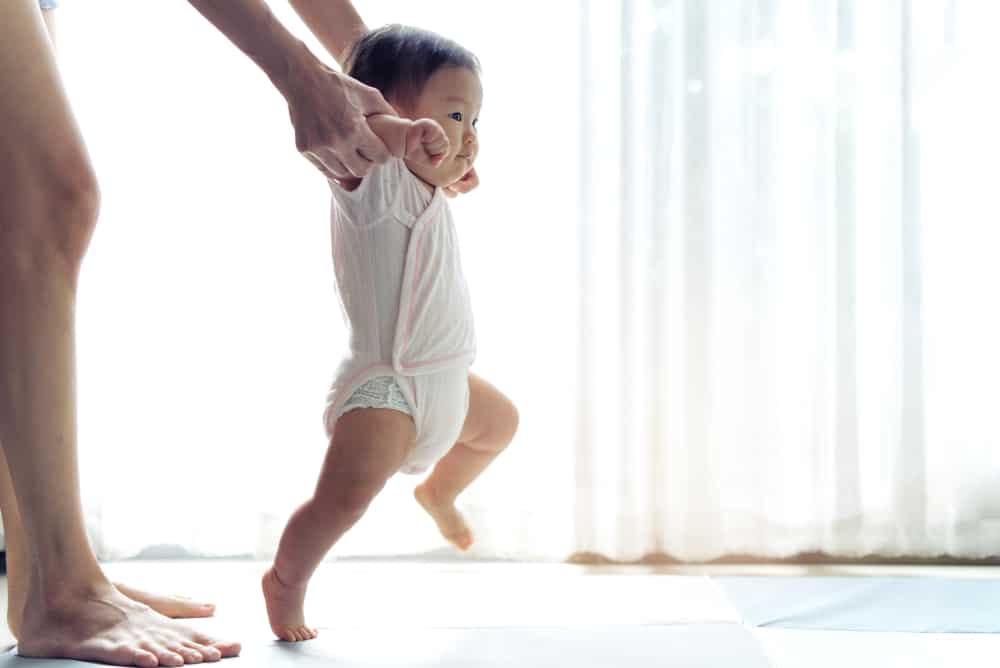 Mom guiding her baby who's learning to walk.