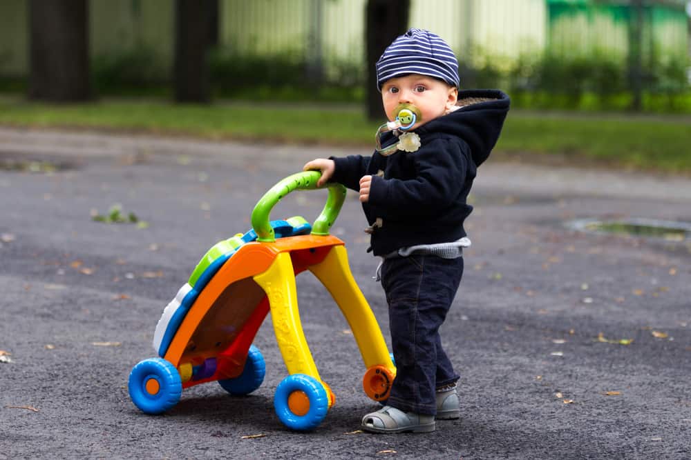 Toys that encourage walking: Baby boy with a push toy in the park.