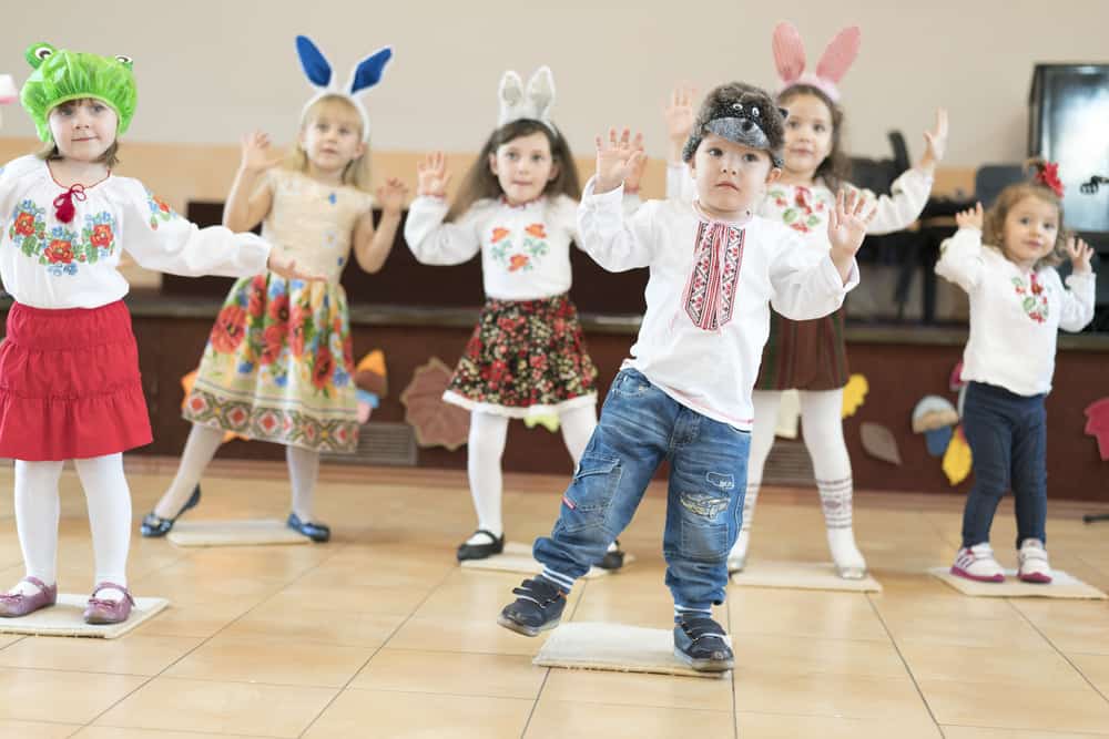 50 Best Music Activities for Kids 4 Music activities for kids: A group of kids in animal headbands and hats dancing.