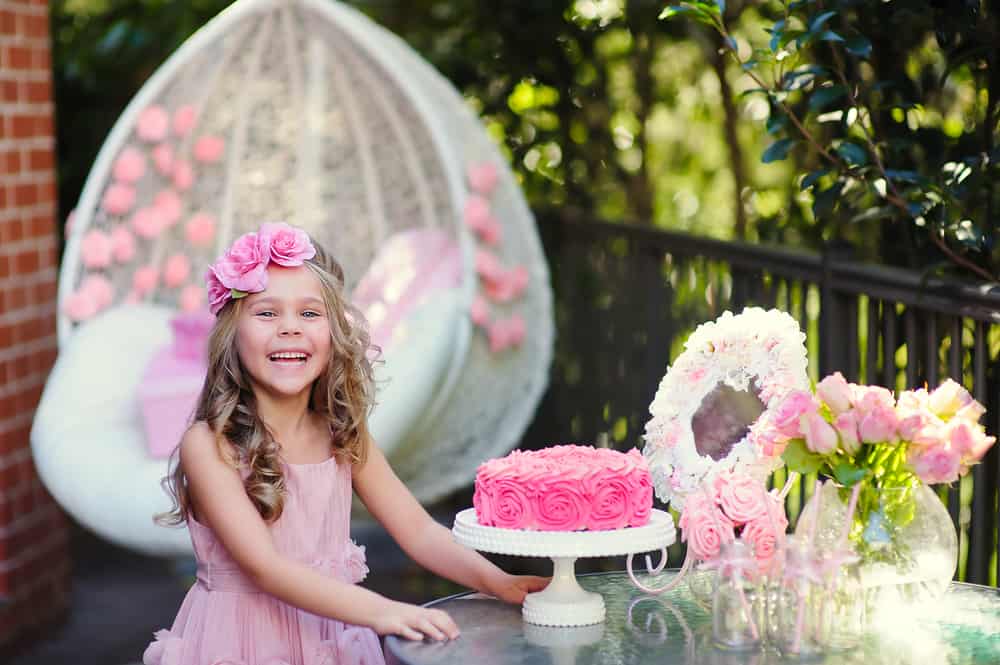 100 Best Kids Birthday Party Ideas 10 Girl celebrating her birthday outdoors with rose cake and flower decors.