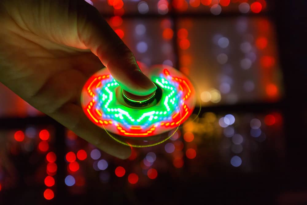 Glow in the dark toys: Girl hand playing with a tri-fidget hand spinner.