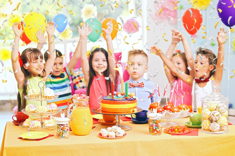 Kids birthday party with balloons, cake, pastries, candies, and confetti.
