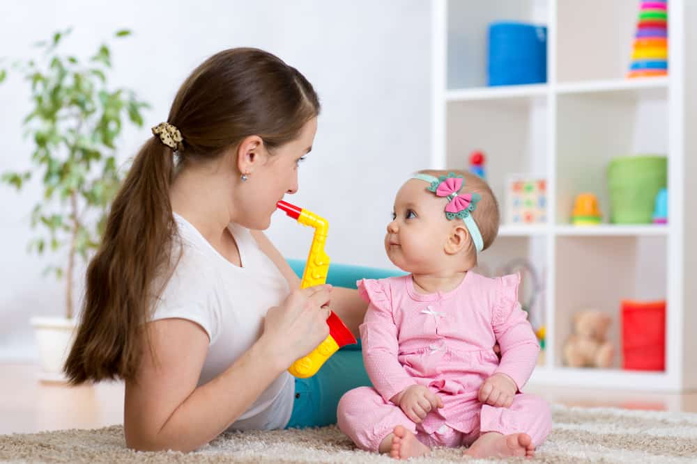 50 Best Music Activities for Kids 2 Mom playing musical toy to her baby girl.