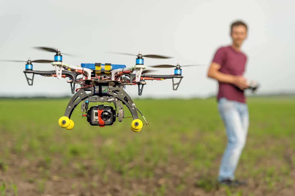 A man piloting a quadcopter in the field.