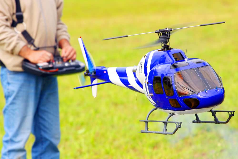 Man piloting a radio controlled helicopter in the field.