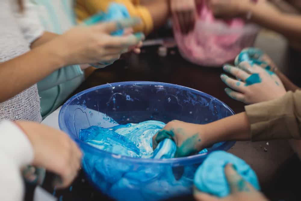100 Best Kids Birthday Party Ideas 16 Kids hands playing slimes.