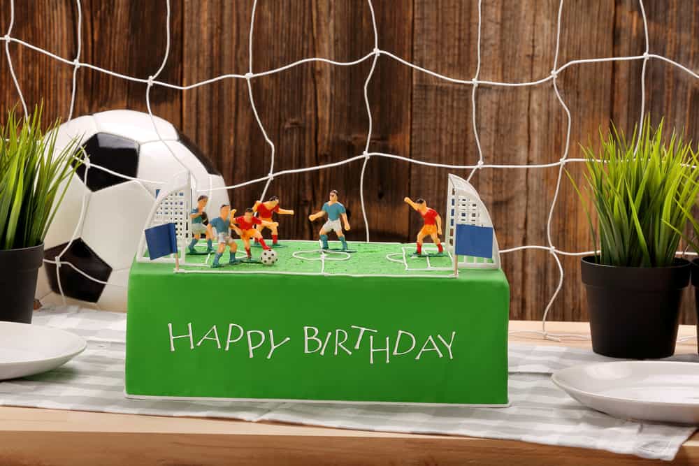 100 Best Kids Birthday Party Ideas 18 Soccer themed birthday party with custom cake against a net and soccer ball.