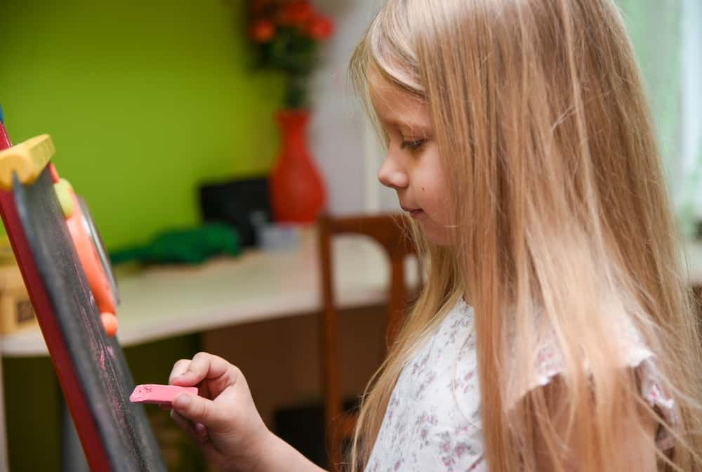 50 Best Music Activities for Kids 8 Little girl writing on a chalkboard at home.