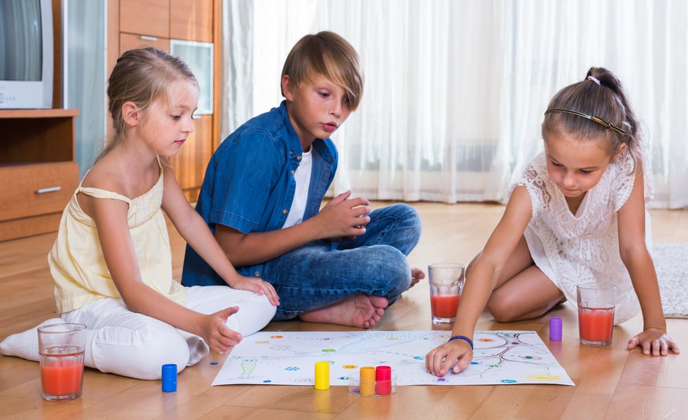 7 to 9-year old kids playing board games on the floor.