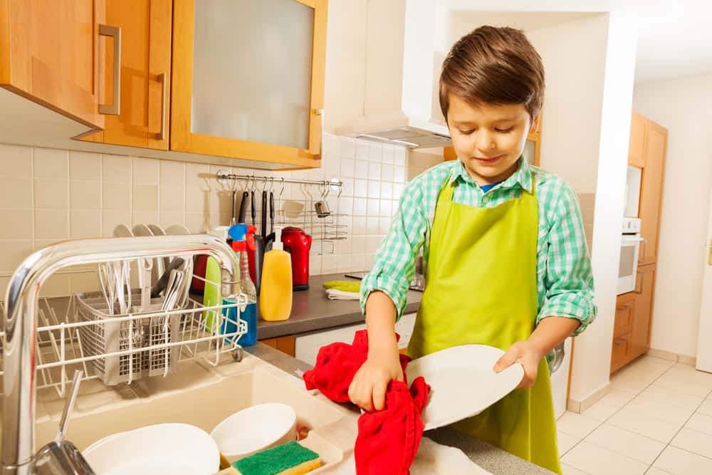 20 Best Chores for 7-9 Year Olds 13 Little boy drying the clean dishes on the sink.