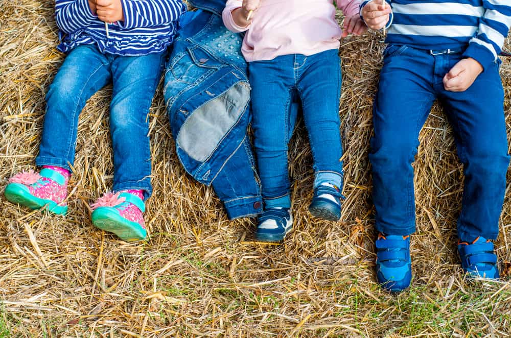Kids in denim pants lying on hayloft.