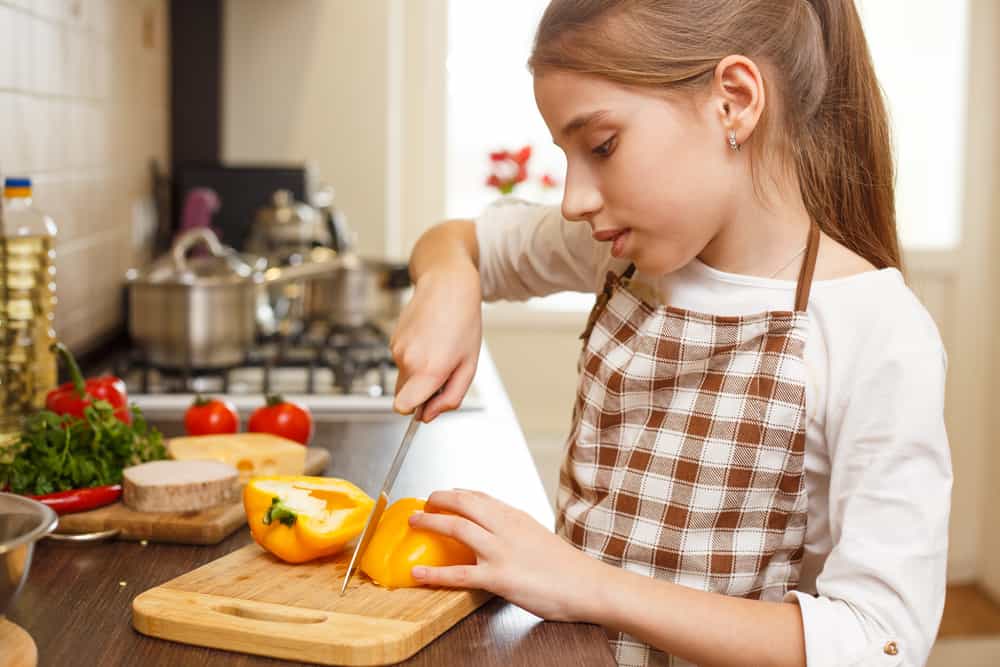 9 Best Chores for 10-12 Year Olds 6 Little girl chopping veggies in the kitchen.