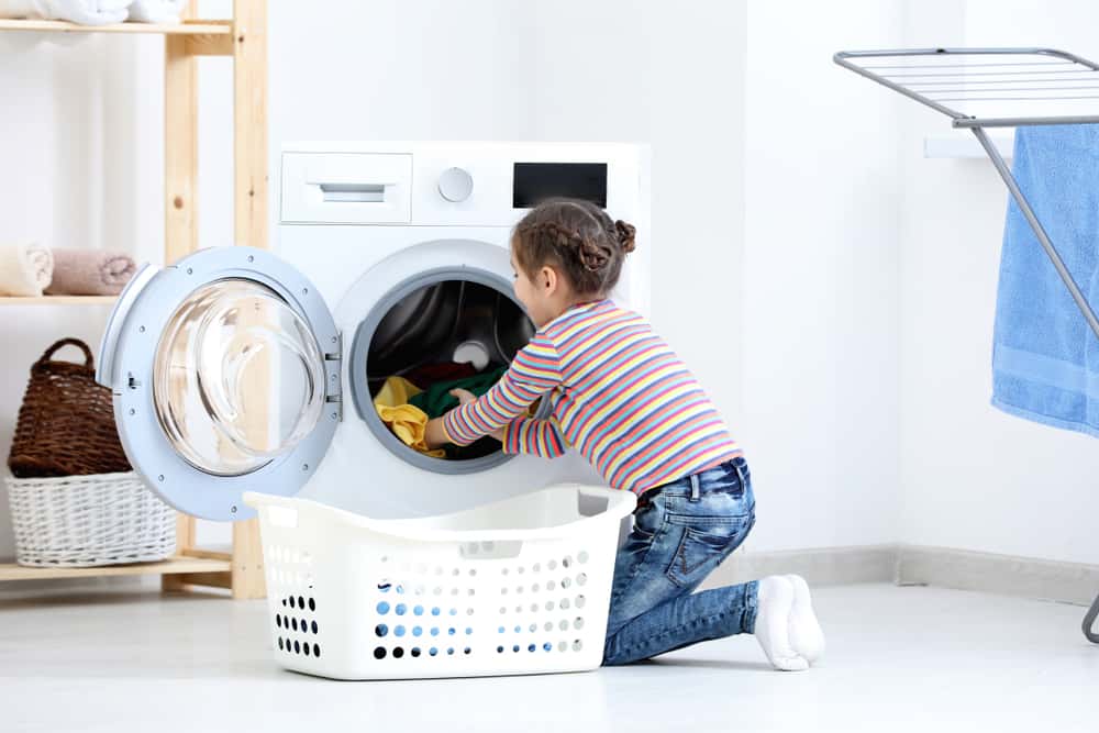 20 Best Chores for 7-9 Year Olds 9 Girl taking out clean clothes from the washing machine.