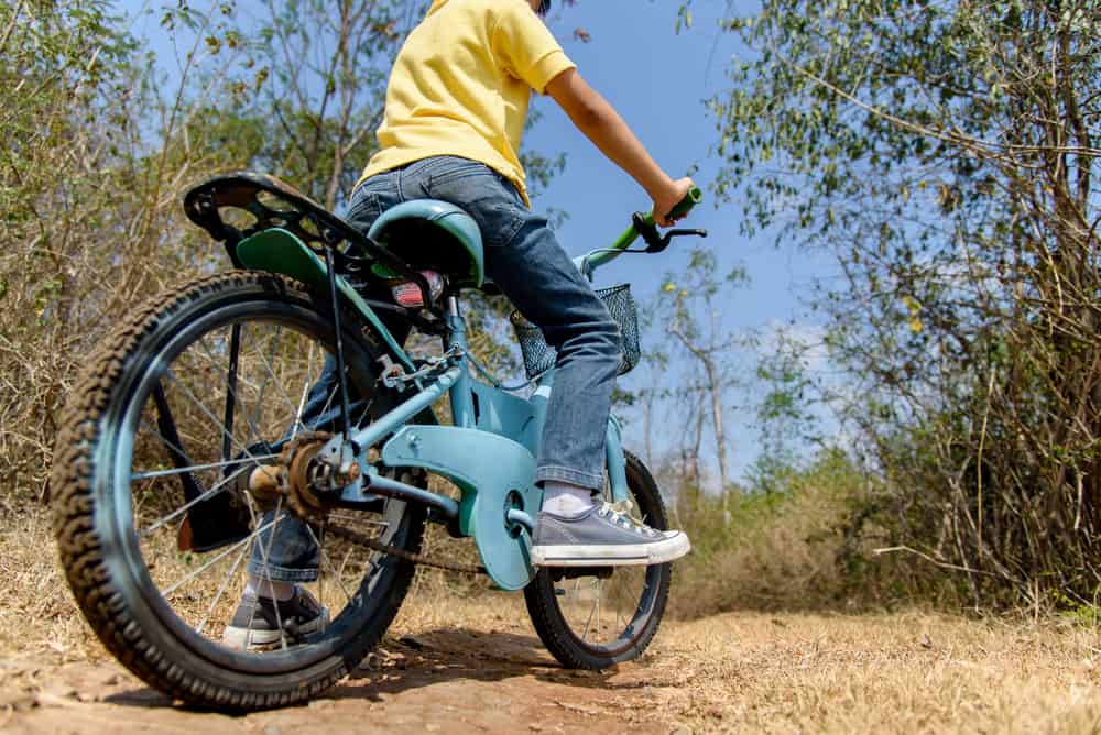 Close-up of a boy riding a bike on a rough road.