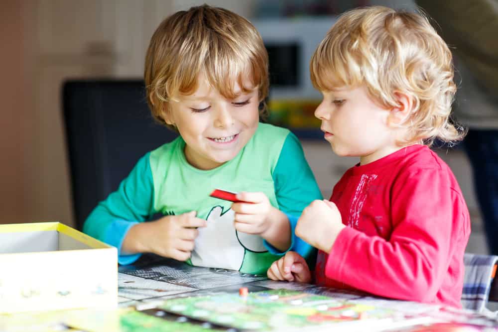Little boys playing board games at home.
