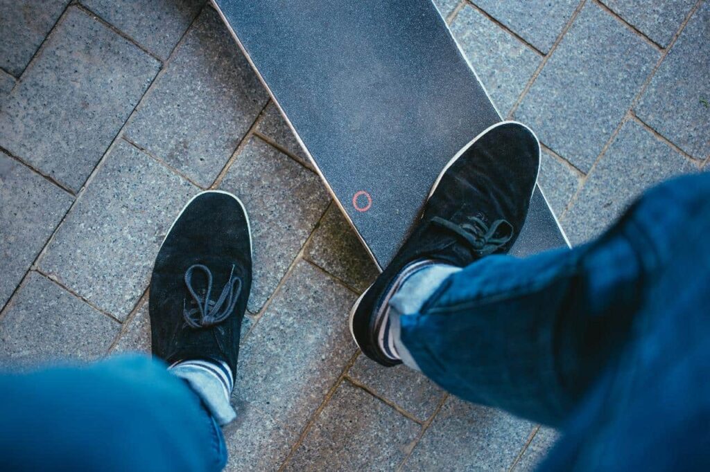 Top view of a foot resting on a skateboard covered in sandpaper.
