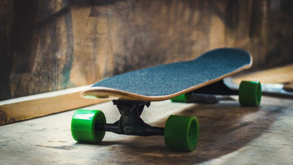 A closer look at a skateboard with green wheels.