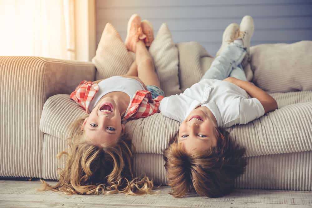 Kids lying on their backs on sofa.