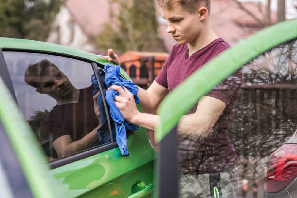 44 Best Chores for Teenagers 13 Teen wiping the window of the car.