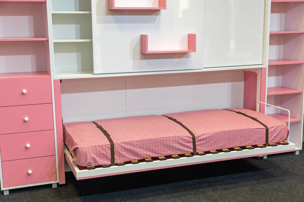 Kid's bedroom with a wall bed surrounded by built-in shelves and drawers.