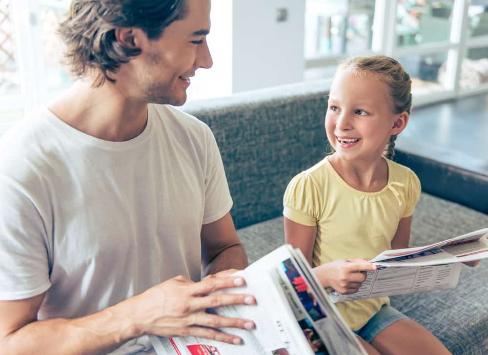 15 Best Chores for 5-6 Year Olds 2 Father and daughter on a couch holding newspapers.