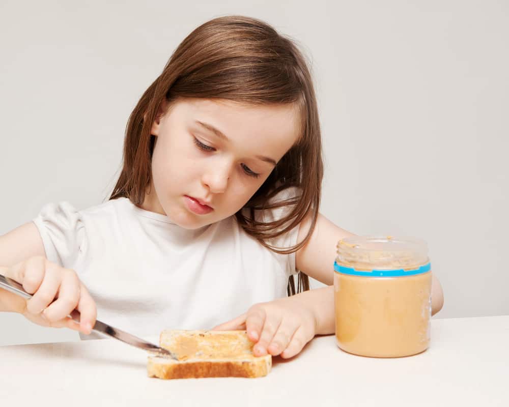 15 Best Chores for 5-6 Year Olds 14 Little girl spreading peanut butter on the sandwich.