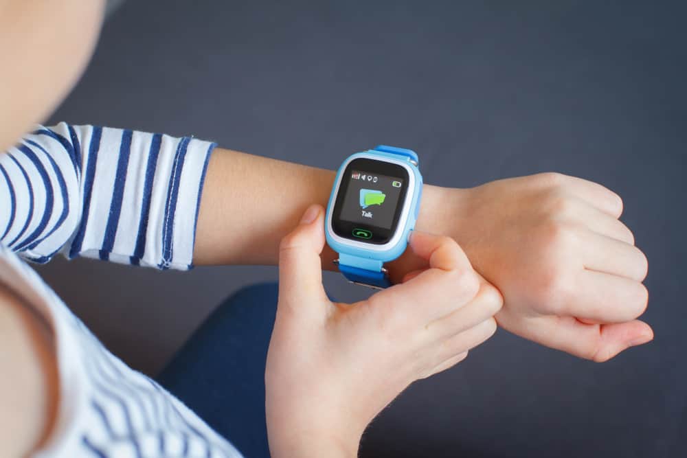 Kid in striped shirt looking at her smart watch.