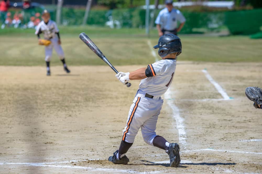 Kids Baseball Bat Sizes: 3 Important Factors (Charts) 1 Back profile of a kid playing baseball on an outdoor field during a game.