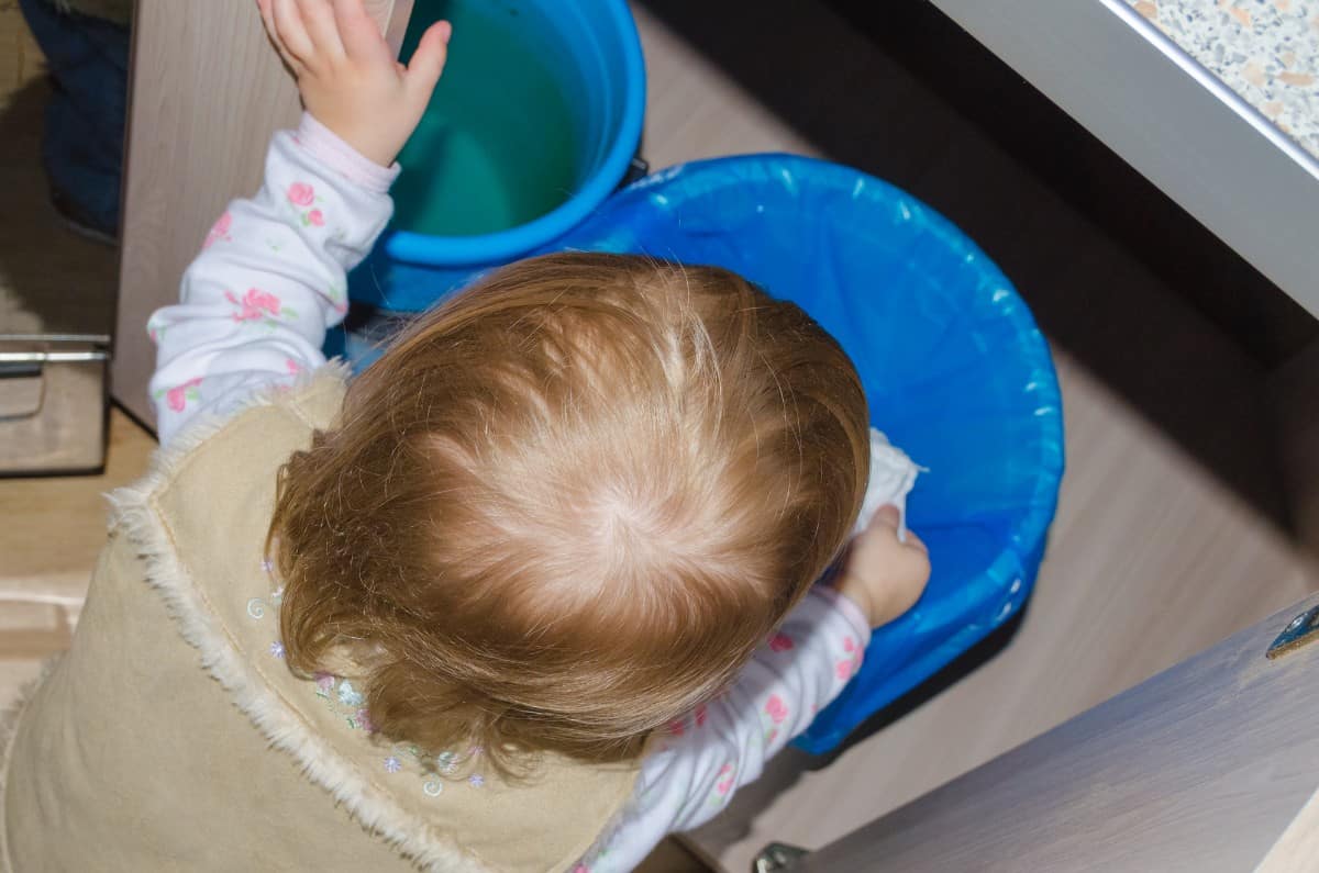 20 Best Chores for 3-4 Year Olds 7 Kid emptying a small bin.