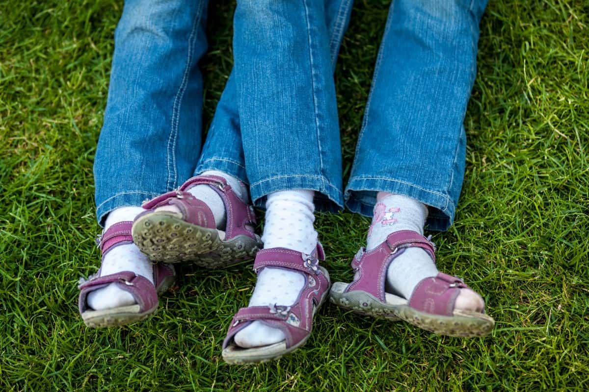 Twin girls wearing denim pants and pink sandals.