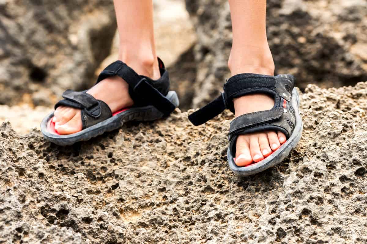 Boy's feet wearing black sandals.