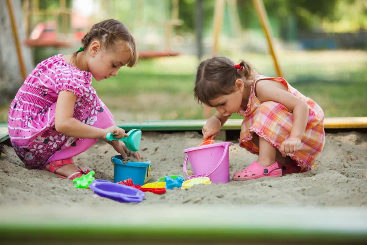 Little girls playing in the sandbox.
