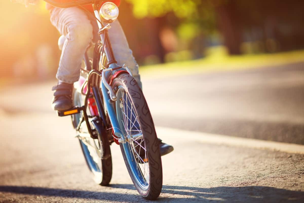 Child riding a bicycle on asphalt road.