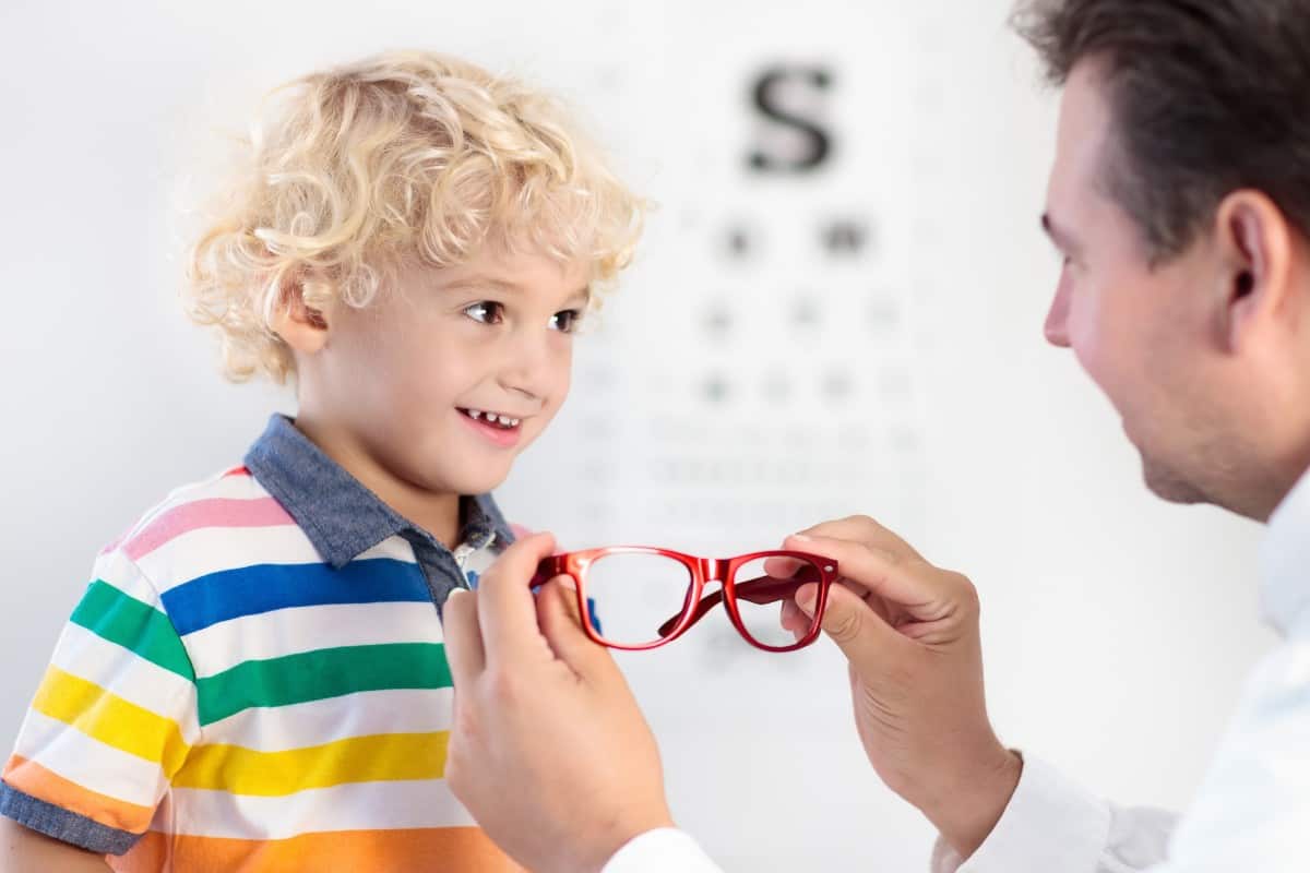 Optometrist prescribing eyeglasses to little boy.