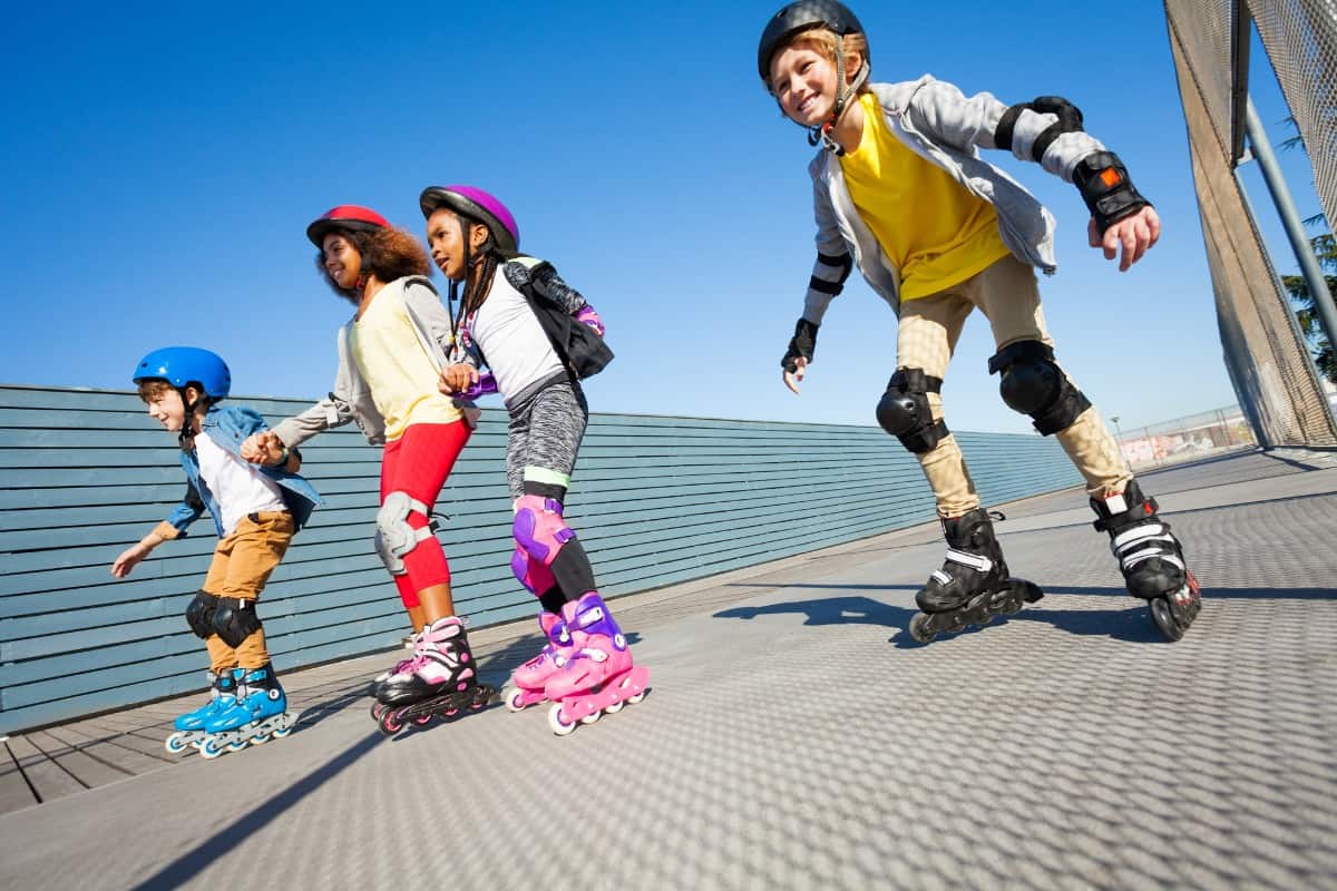 A group of kids rollerblading on the road.