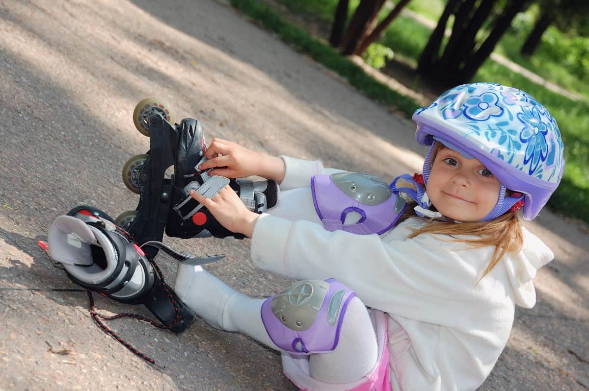 Little girl putting on rollerblades.