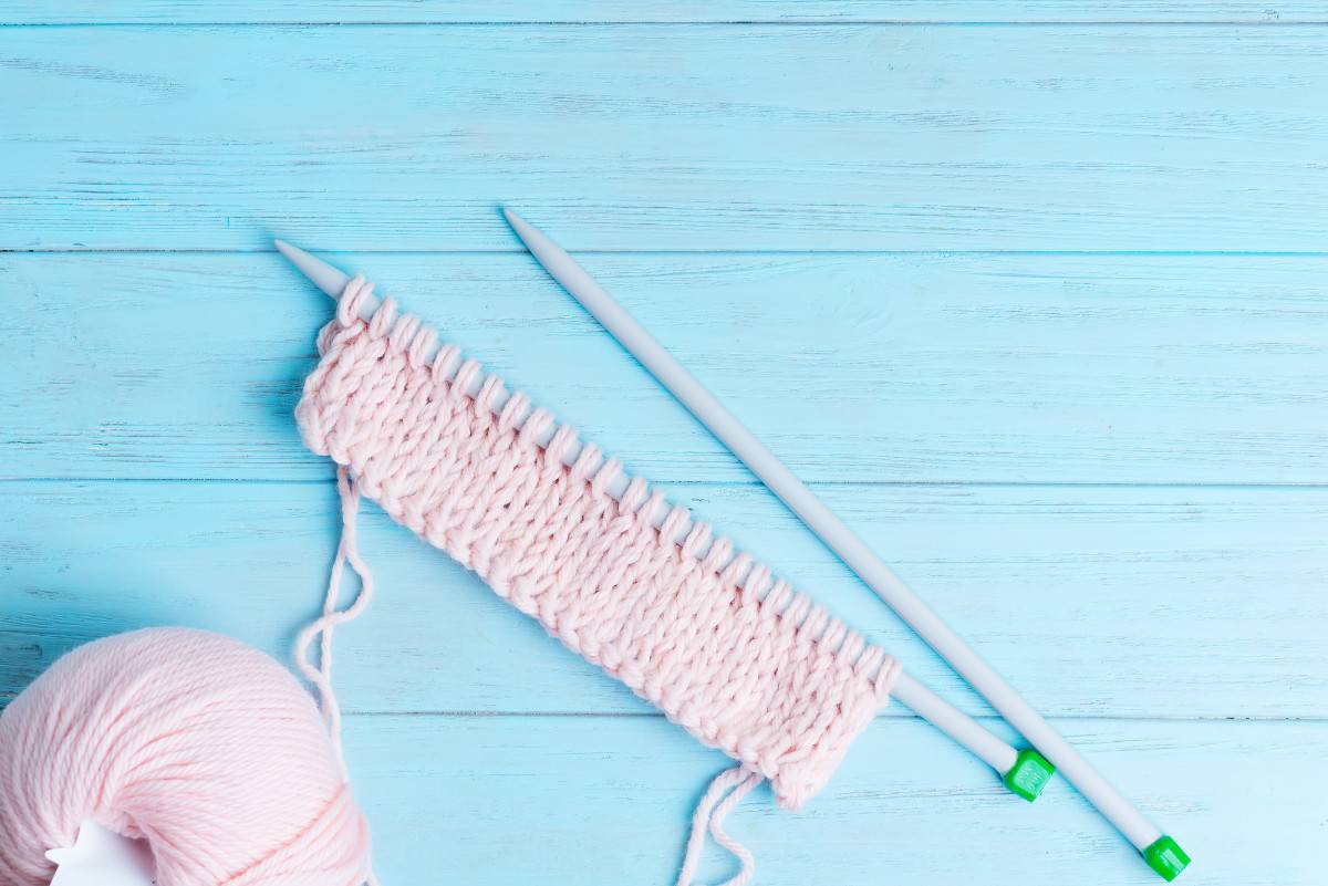 Pink knitting yarn against blue wood planks.