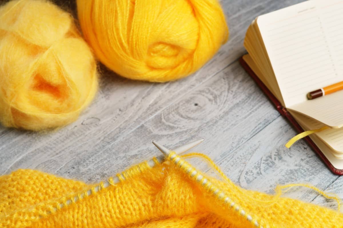 Yellow knitting yarns with needles and pencil.