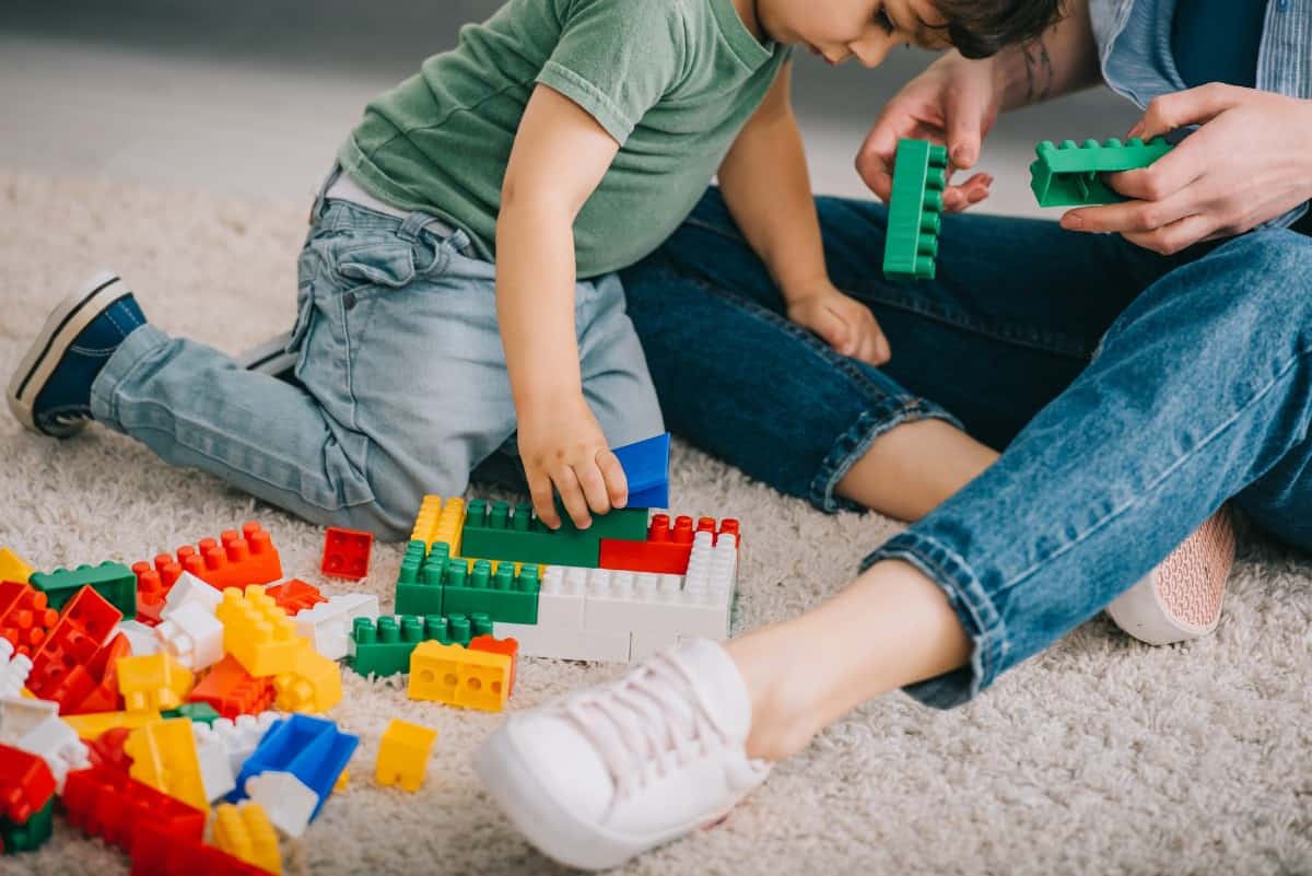 Mother and son playing Lego on carpet.