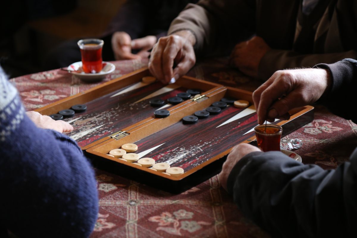 Three person playing Backgammon and glass of tea.
