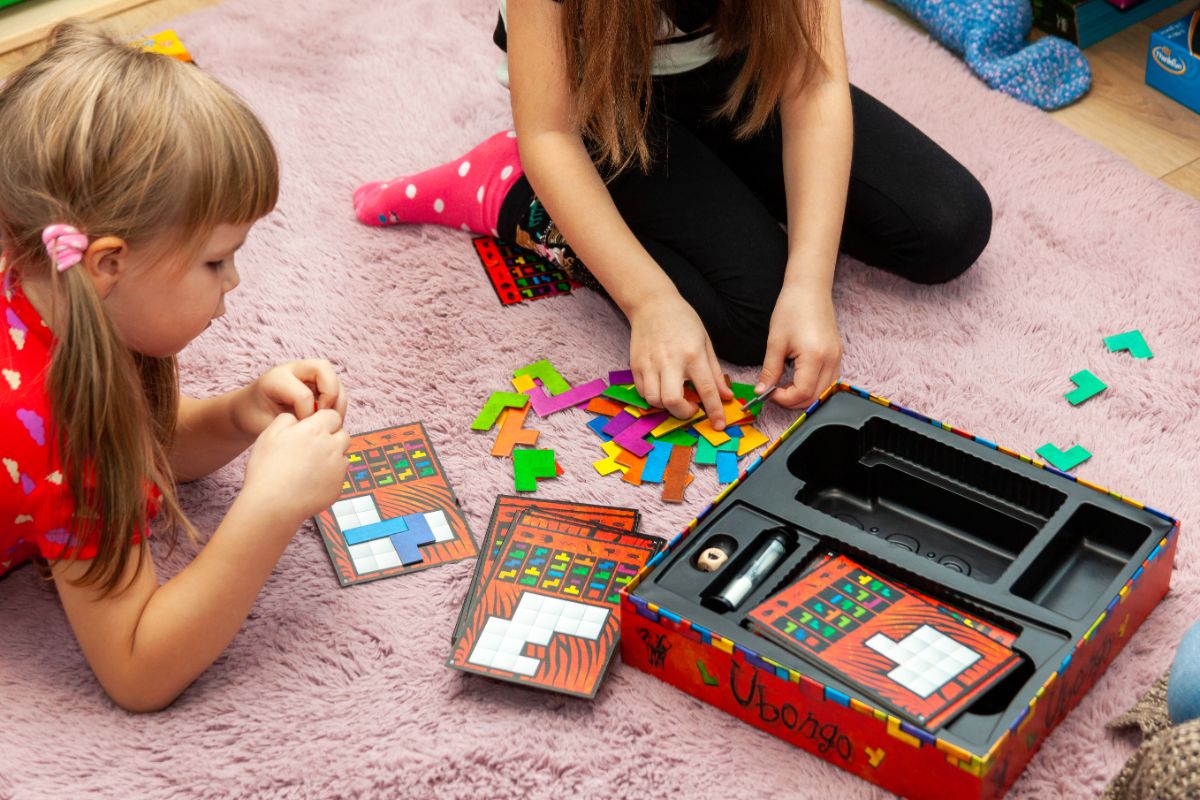 Children playing card games on a rug.