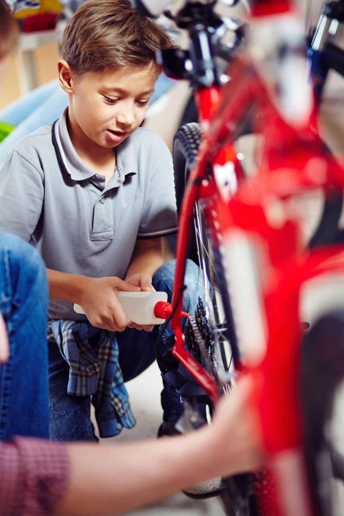 Mountain Bike Chain: How Often Should You Oil? 2 Young boy applying oil on a red bike.