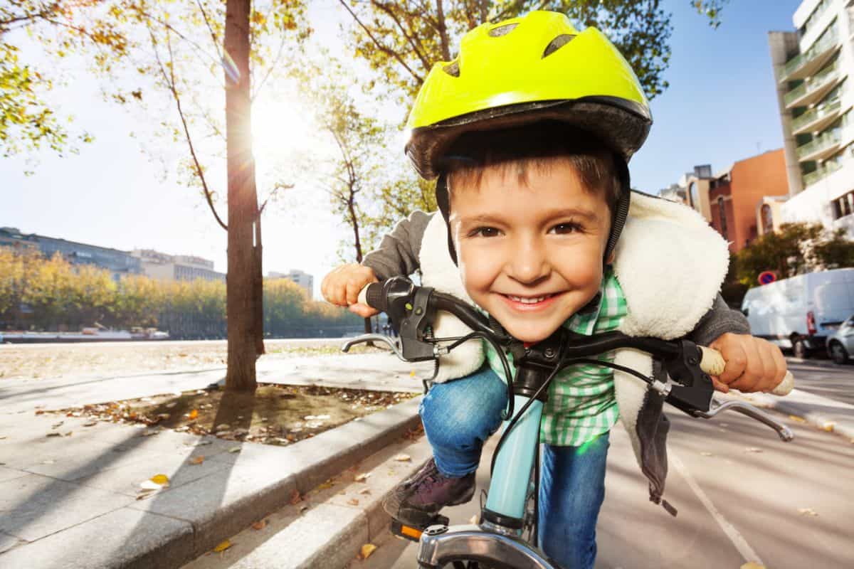 Smiling young boy on a bike looking straight at the camera.