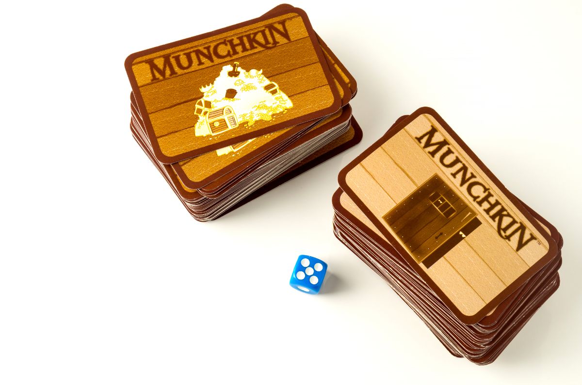 17 Amazing Board Games Similar to Sorry 8 Munchkin cards and its dice on a white background.